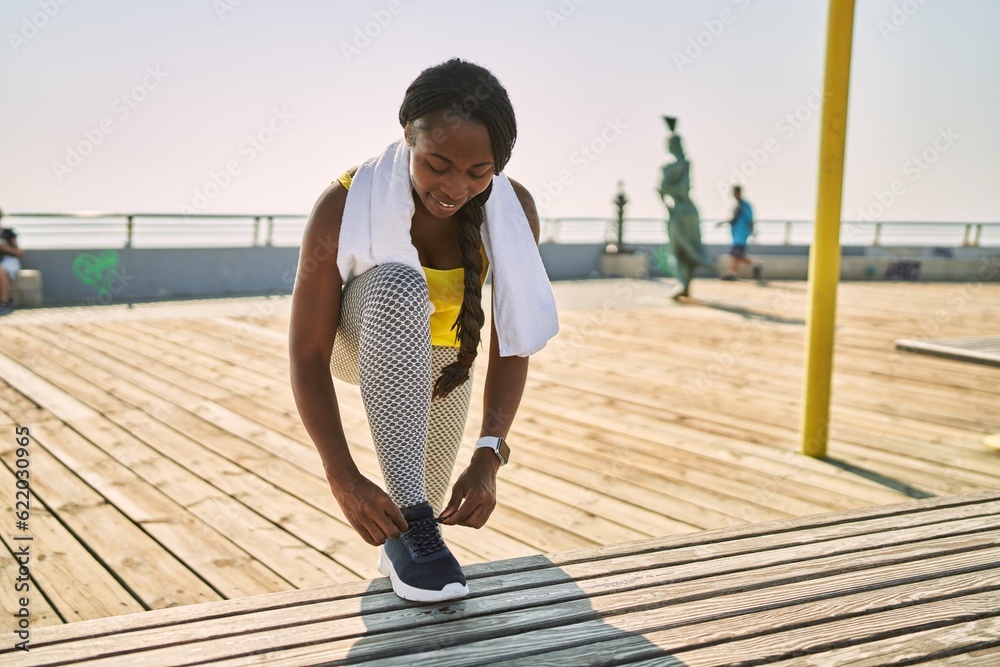 Sticker african american woman smiling confident tying shoe at seaside