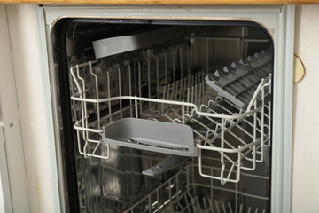 Open dishwasher with metal shelves for dishes