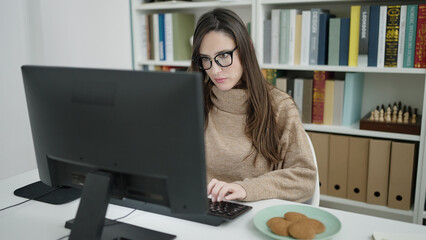 Beautiful hispanic woman student using computer studying at library university