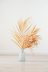 Stylish modern dry palm leaves in glass vase on a wooden light floor in room in Scandinavian style. Art deco, boho gift for anniversary, birthday, mother's day