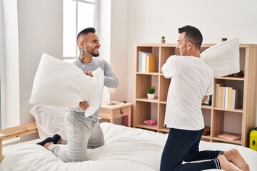 Obraz premium Two men couple fighting with pillows at bedroom