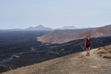 Woman hiker walking a trail through the volcanic landscape of Lanzarote, Canary Islands, Spain.
