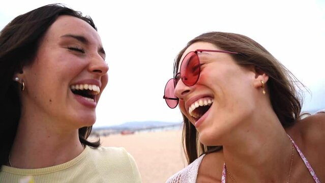 Three caucasian female friends outdoors at the beach having fun and laughing together wearing swimwear. young women enjoying summer vacation.