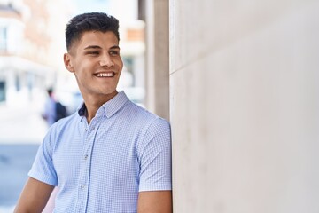 Young hispanic man smiling confident looking to the side at street