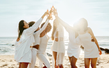 Group of ladies drinking champagne while having a hen party on the beach, women hanging out on...