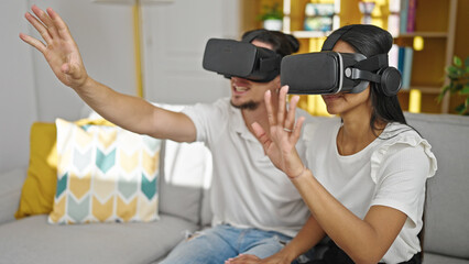 Man and woman couple playing video game using virtual reality glasses at home