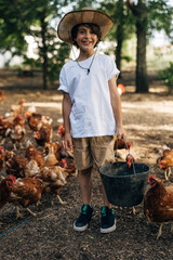 front view of a cute Caucasian boy on a chicken farm feeding the chickens.