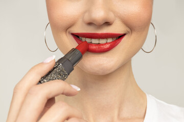 The girl paints her lips with red lipstick