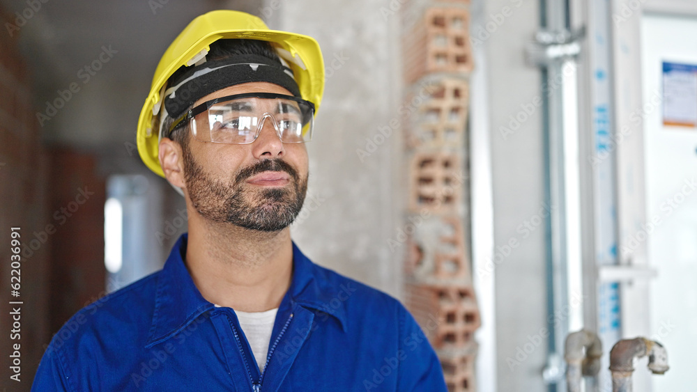 Sticker young hispanic man worker wearing hardhat at construction site