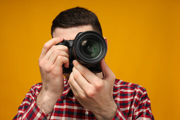 A man takes pictures, a photographer, on a yellow background