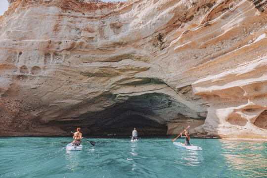 Group of sup boarders enters huge limestone cave on a sea coast