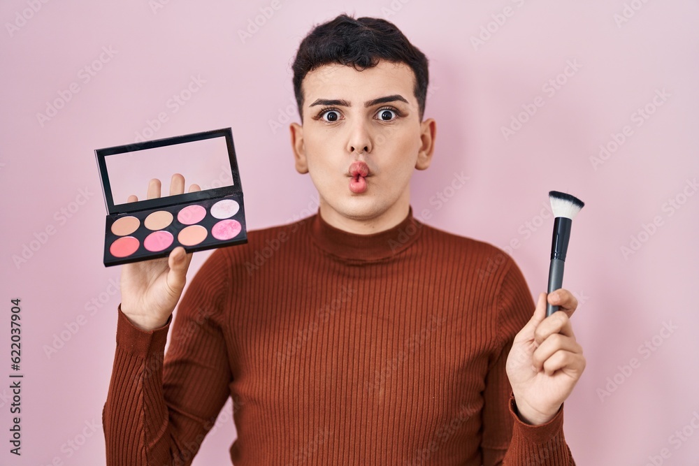 Sticker Non binary person holding makeup brush and blush making fish face with mouth and squinting eyes, crazy and comical.