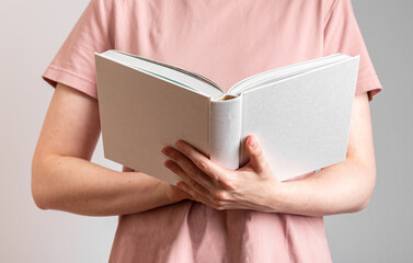 Hand holding white open book, reader student