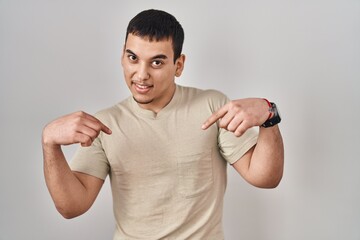 Young arab man wearing casual t shirt looking confident with smile on face, pointing oneself with...
