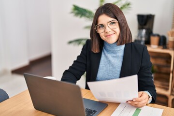 Fototapeta na wymiar Young beautiful hispanic woman business worker using laptop reading document at office
