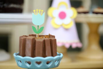 Um bolo encantador decorado com barrinhas de chocolate e uma encantadora flor de papel, tornando a festa infantil ainda mais especial.