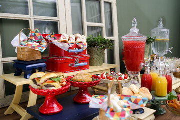 Uma mesa colorida e vibrante em um evento infantil, repleta de alimentos saudáveis, frescos e deliciosos. Uma festa que promove a alimentação equilibrada e a diversão saudável para as crianças.