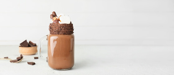 Mason jar of sweet hot chocolate on light background with space for text