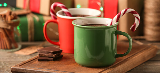 Mugs of delicious hot chocolate with candy canes on table