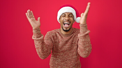 African american man wearing christmas hat clapping hands applause over isolated red background
