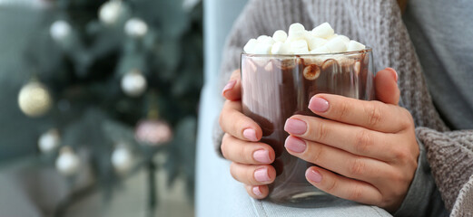 Woman with cup of hot chocolate and marshmallows at home, closeup