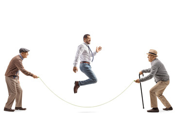 Full length shot of two senior men playing skipping rope with a younger man