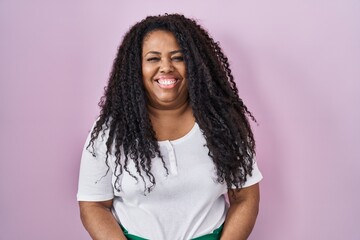 Plus size hispanic woman standing over pink background with a happy and cool smile on face. lucky...