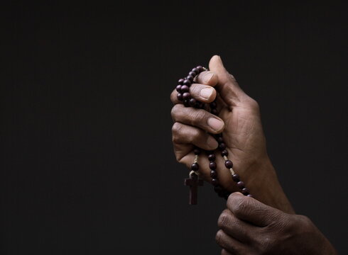 man praying to god with hands together Caribbean man praying on black background with people stock image sock photo