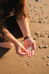 Close up of woman's hands collecting sea glass on sandy shore