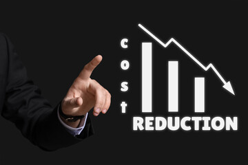 Businessman using virtual screen on dark background. Cost reduction