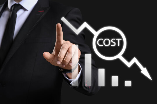 Businessman using virtual screen on dark background. Cost reduction