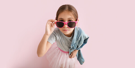 Cute fashionable girl with stylish sunglasses on pink background