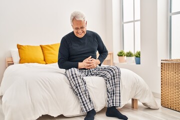 Fototapeta premium Senior man suffering for stomache pain sitting on bed at bedroom