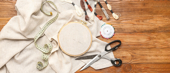 Embroidery hoop with canvas, threads, pins, measuring tape and scissors on wooden background © Pixel-Shot