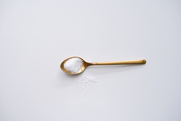 Golden spoon laying on light background with sugar. Ingredients for homemade cooking with empty space for text