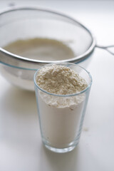 Ready to cook, white flour for making dough. Glass beaker with white flour in light kitchen, closeup