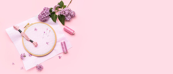Wooden embroidery hoop with canvas, threads, pins and lilac flowers on pink background with space for text © Pixel-Shot