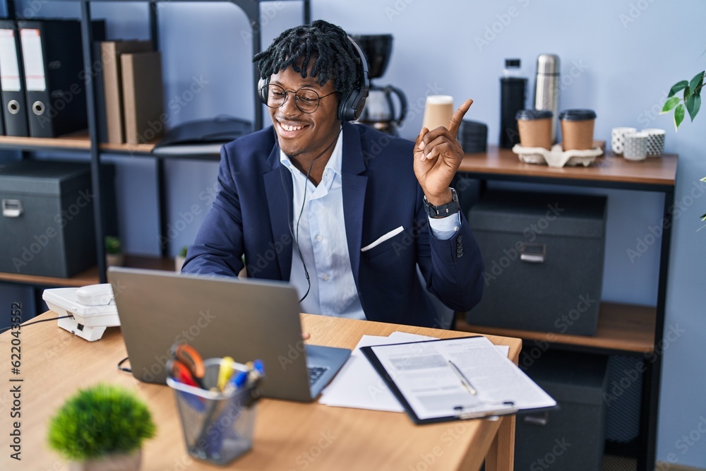 Sticker young african man with dreadlocks working at the office wearing headset smiling happy pointing with 