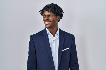 Young african man with dreadlocks wearing business jacket over white background looking away to...