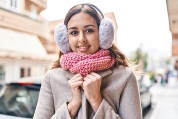 Young beautiful hispanic woman smiling confident wearing scarf and earmuff at street