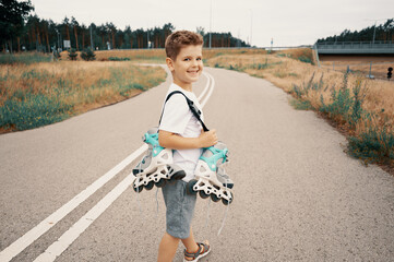 Smiling boy 7 years old carries roller skates