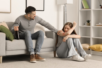 Bruised young woman and her drunk husband at home. Domestic violence concept