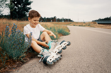 Smiling boy 7 years old puts on roller skates