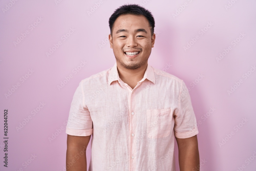 Sticker Chinese young man standing over pink background with a happy and cool smile on face. lucky person.