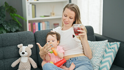 Mother and daughter drinking tea while playing with hoops at home