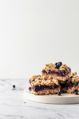 Vegan baked oatmeal squares with fresh blueberry on white tray on marble background with text space