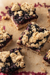 Vegan baked oatmeal squares with fresh blueberry on beige parchment paper