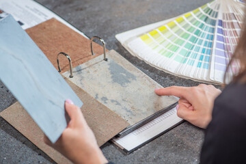 The choice of natural stone for interior decoration. A woman architect selects a shade of stone from samples close-up. The concept of renovation in the interior.