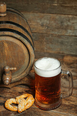 Mug of cold beer, pretzel and barrel on wooden background. Oktoberfest celebration