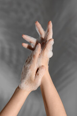 Hands in soap foam on grey  background